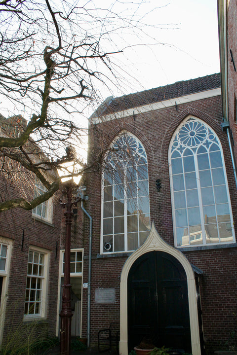 Historic Amsterdam hofje with gothic windows, home to the Atelier Marx studio of artist Marjolein Marx — where contemporary art meets serene heritage architecture.
